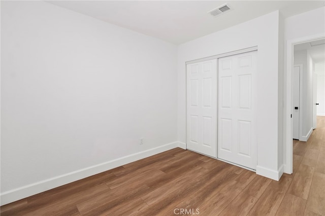 unfurnished bedroom featuring wood-type flooring and a closet