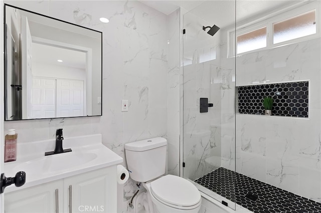 bathroom with vanity, a tile shower, tile walls, and toilet