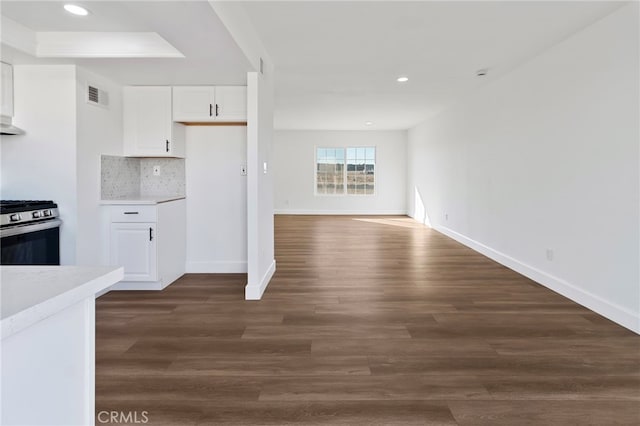 kitchen with backsplash, gas range, dark wood-type flooring, and white cabinets