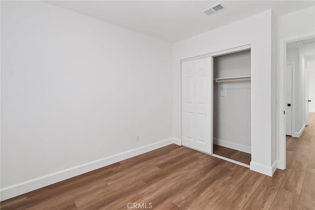 unfurnished bedroom with wood-type flooring and a closet