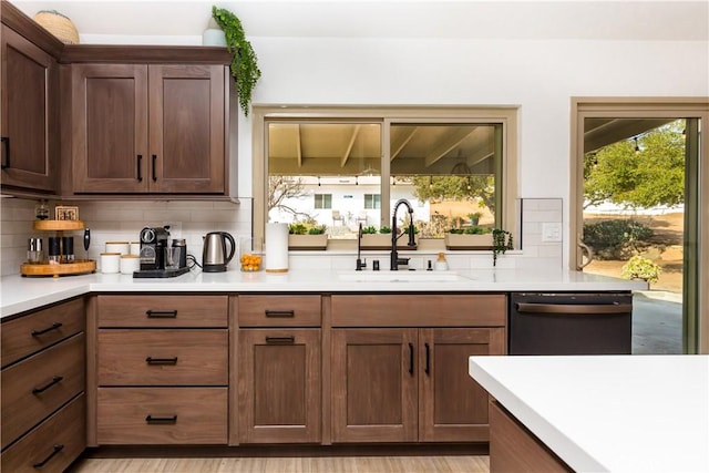 kitchen with sink, decorative backsplash, light hardwood / wood-style flooring, and dishwasher