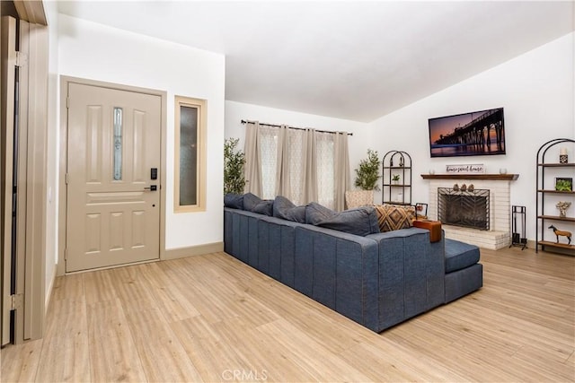 living room with a fireplace, vaulted ceiling, and light hardwood / wood-style floors