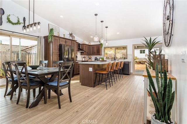 dining space with vaulted ceiling and light wood-type flooring