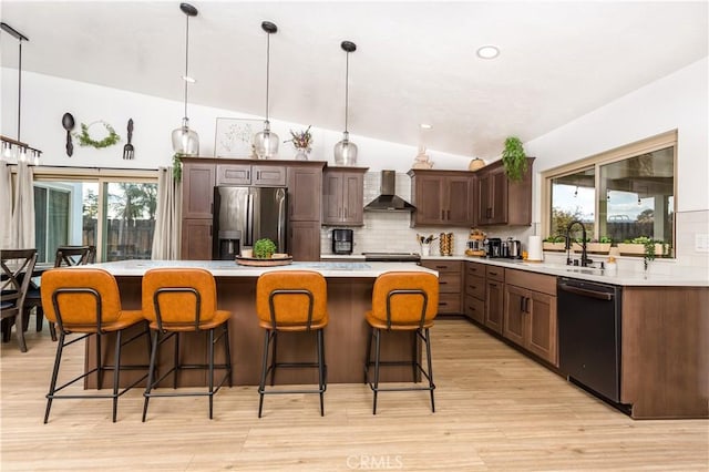 kitchen featuring wall chimney range hood, a kitchen island, black dishwasher, and stainless steel refrigerator with ice dispenser