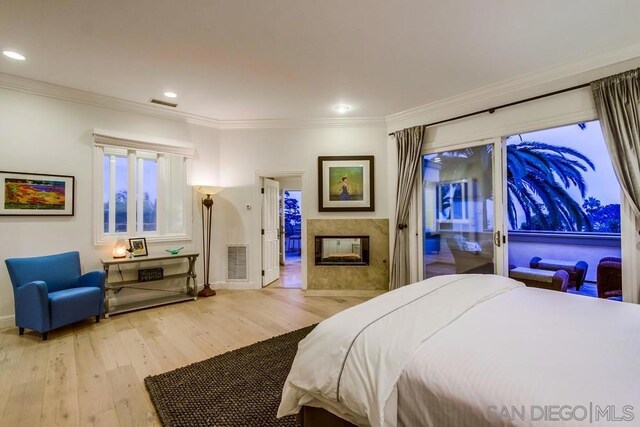 bedroom featuring crown molding, access to outside, light hardwood / wood-style floors, and a multi sided fireplace