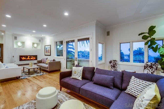 living room featuring crown molding, wood-type flooring, and a healthy amount of sunlight