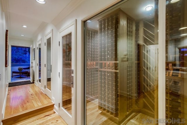 wine cellar featuring hardwood / wood-style flooring and crown molding