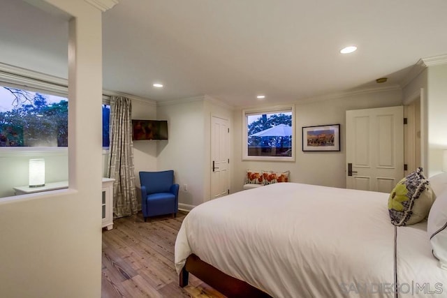 bedroom with ornamental molding and light hardwood / wood-style floors