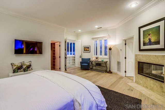 bedroom with a fireplace, light hardwood / wood-style flooring, and ornamental molding