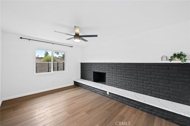 unfurnished living room with a brick fireplace, hardwood / wood-style floors, and ceiling fan