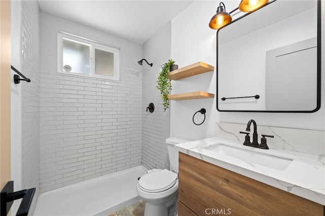 bathroom with vanity, tiled shower, and toilet