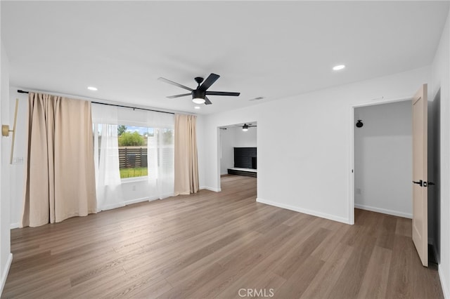 empty room with ceiling fan and light hardwood / wood-style floors