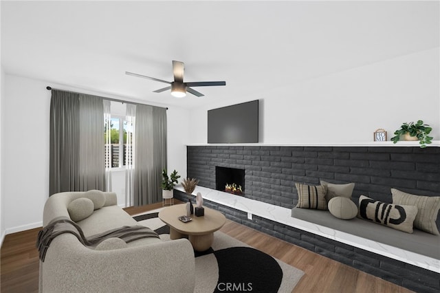 living room featuring ceiling fan, dark wood-type flooring, and a fireplace