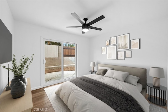 bedroom featuring access to exterior, dark hardwood / wood-style floors, and ceiling fan