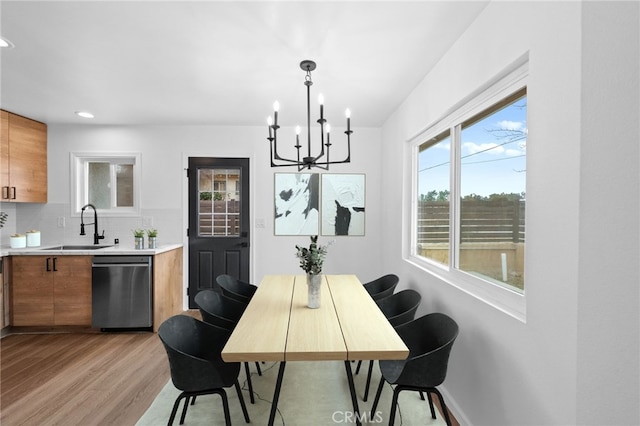 dining room featuring sink, an inviting chandelier, and light hardwood / wood-style flooring