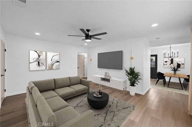 living room with hardwood / wood-style flooring and ceiling fan with notable chandelier