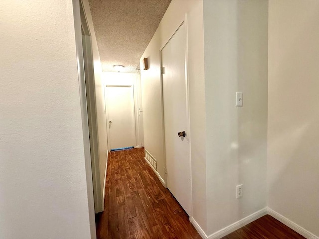 hallway featuring dark hardwood / wood-style flooring and a textured ceiling