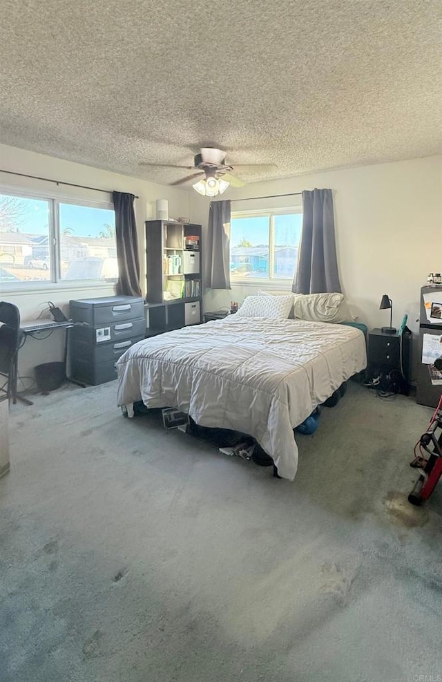 carpeted bedroom featuring a textured ceiling and ceiling fan