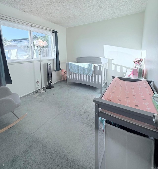 carpeted bedroom featuring a nursery area and a textured ceiling