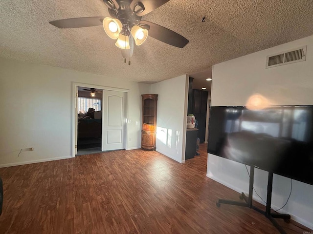 unfurnished bedroom with a textured ceiling, wood finished floors, a ceiling fan, visible vents, and baseboards