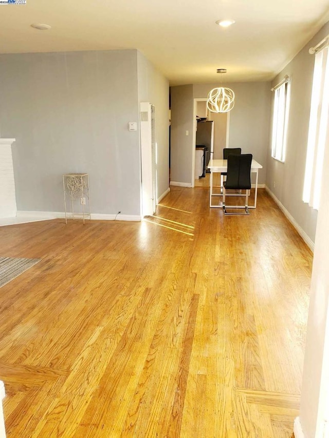 unfurnished living room featuring a chandelier and light wood-type flooring