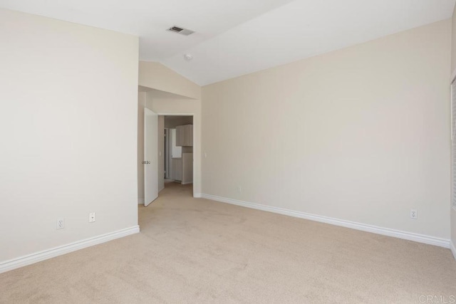 carpeted empty room featuring vaulted ceiling