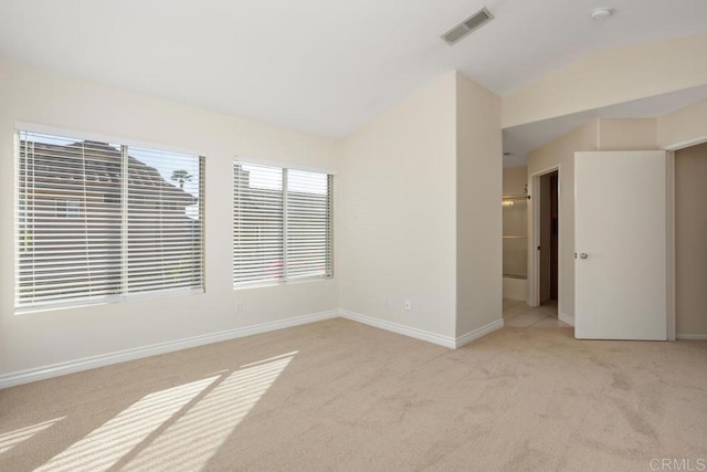 unfurnished room with light colored carpet and vaulted ceiling