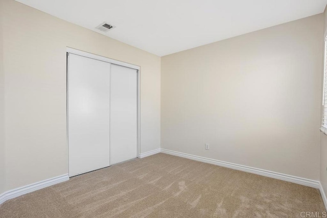 unfurnished bedroom with light carpet and a closet