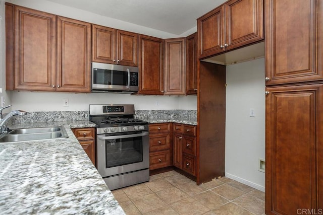 kitchen with light stone counters, sink, light tile patterned floors, and appliances with stainless steel finishes