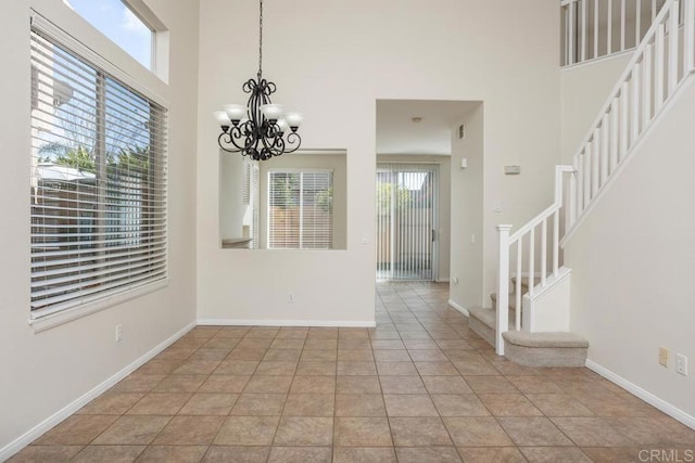 unfurnished dining area featuring light tile patterned flooring, a towering ceiling, and a chandelier