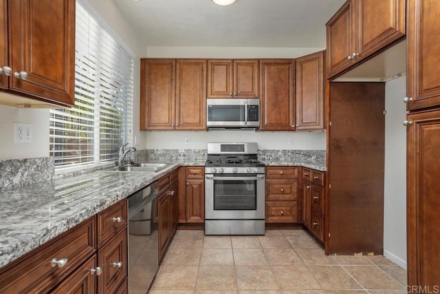 kitchen featuring light stone counters, sink, light tile patterned flooring, and appliances with stainless steel finishes