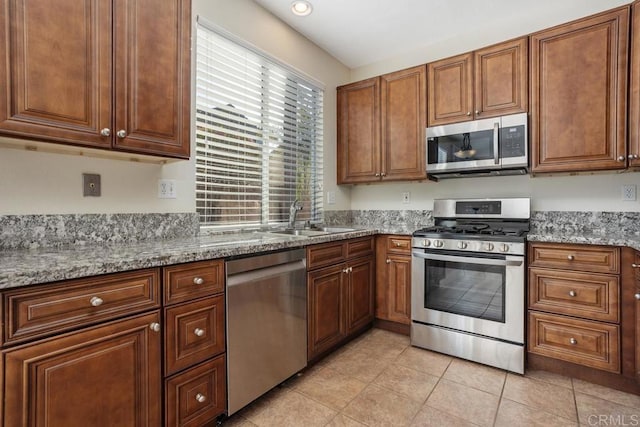 kitchen featuring stainless steel appliances, light tile patterned flooring, light stone countertops, and sink