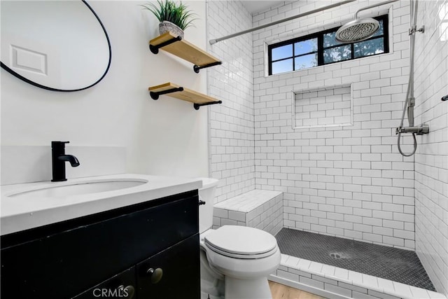 bathroom featuring vanity, toilet, and tiled shower