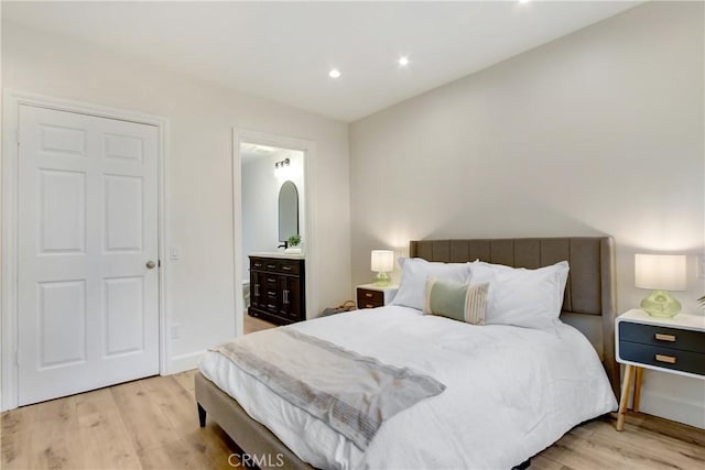 bedroom featuring connected bathroom and light hardwood / wood-style flooring