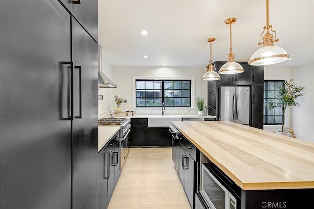 kitchen featuring wood counters, sink, built in appliances, a kitchen island, and pendant lighting