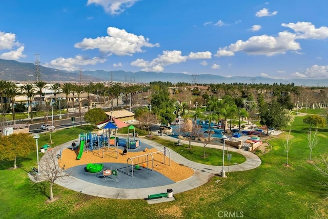 view of community featuring a mountain view, a lawn, and a playground