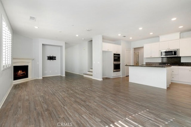 kitchen featuring a kitchen island, white cabinetry, appliances with stainless steel finishes, and dark hardwood / wood-style flooring