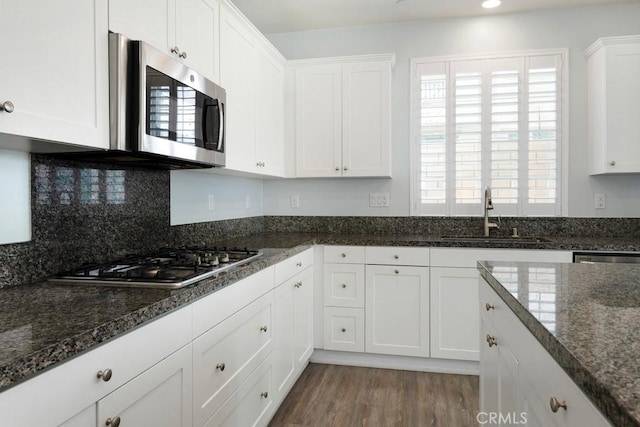 kitchen featuring white cabinetry, appliances with stainless steel finishes, sink, and dark stone countertops