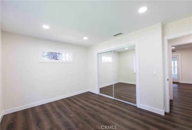 unfurnished bedroom with dark hardwood / wood-style floors and a closet