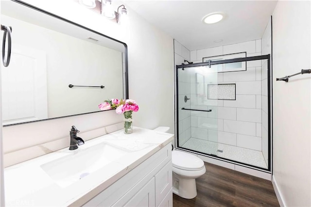 bathroom featuring vanity, wood-type flooring, a shower with shower door, and toilet