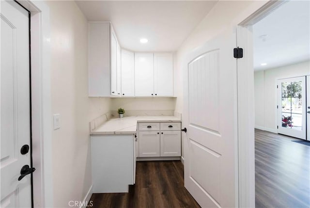 kitchen with dark hardwood / wood-style flooring, light stone countertops, and white cabinets