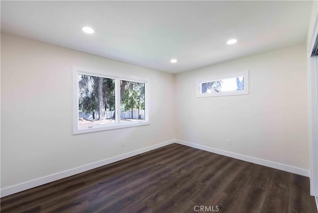 spare room featuring a healthy amount of sunlight and dark hardwood / wood-style floors