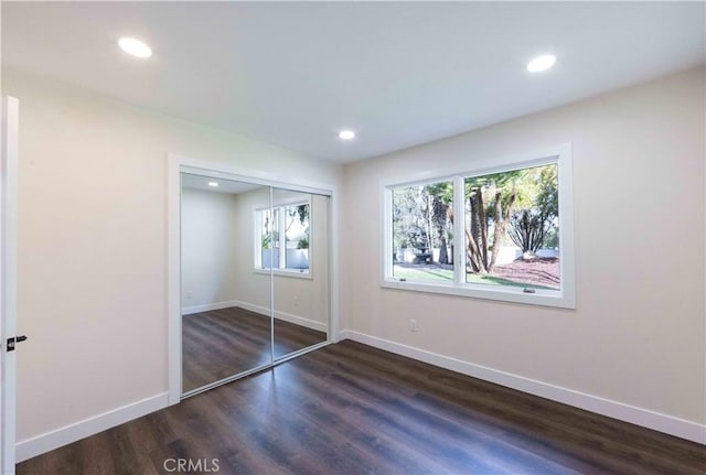 unfurnished bedroom with dark hardwood / wood-style flooring and a closet