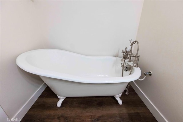 bathroom with hardwood / wood-style floors and a tub to relax in