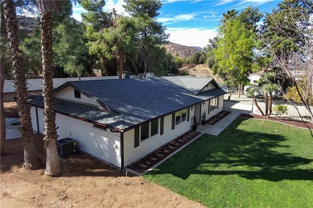 view of side of property with cooling unit, a mountain view, and a yard