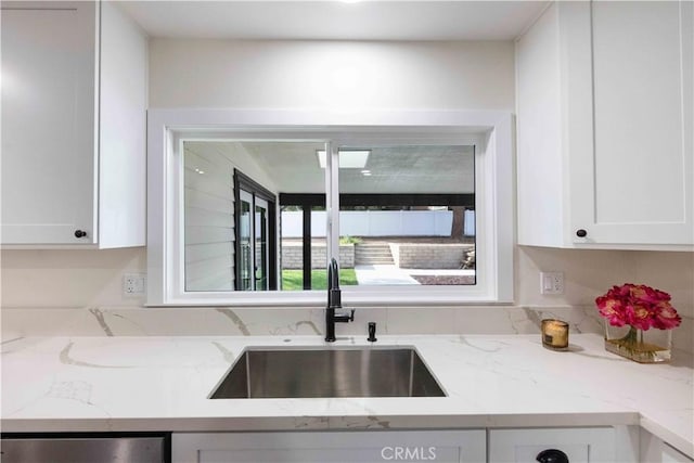 kitchen with white cabinetry, light stone countertops, sink, and stainless steel dishwasher