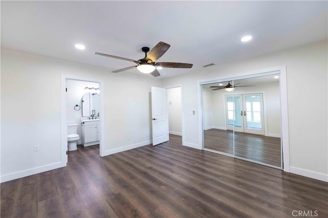 unfurnished bedroom featuring dark wood-type flooring, ceiling fan, ensuite bathroom, and a closet