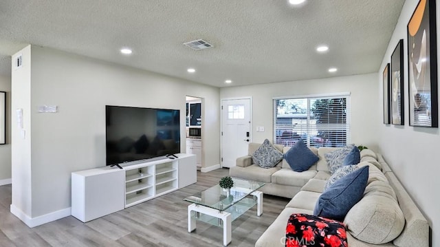 living room featuring a textured ceiling and light wood-type flooring