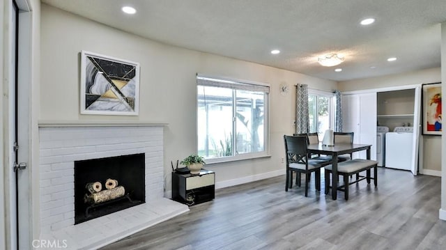 dining area with baseboards, washer and clothes dryer, wood finished floors, a fireplace, and recessed lighting