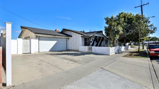 view of front facade with driveway, board and batten siding, an attached garage, and fence